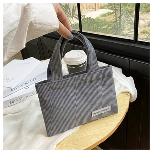 Détail du sac à main en velours côtelé gris avec étiquette de marque et texture côtelée