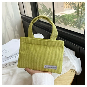 Détail d'un sac cabas en velours côtelé vert avec texture rayée et étiquette