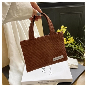 Détail d'un mini sac cabas en velours côtelé marron avec étiquette tissée et texture douce