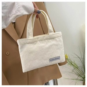 Détail du sac cabas en velours côtelé crème montrant le tissu et l'étiquette logo