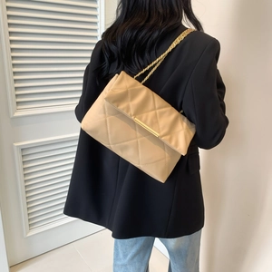 Elegant beige quilted leather shoulder bag with gold chain strap worn by a model