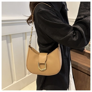 Detail of camel crescent shoulder bag featuring gold U-shaped buckle and chain strap