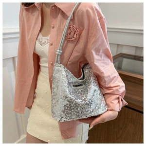 Silberne Pailletten-Tasche mit Fashion-Tag an einem Modell in rosa Kleidung