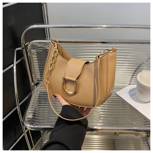 Detail of khaki crescent underarm bag showing golden U-shaped hardware and metal chain strap