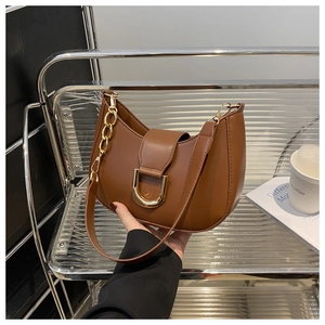 Detail of brown textured hobo bag with gold D-buckle and chain strap in street style