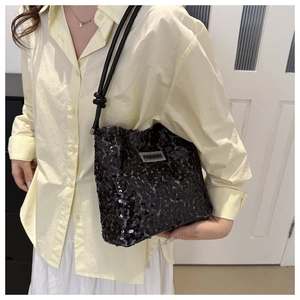 Detailansicht der schwarzen Pailletten-Beuteltasche mit FASHION-Label und Knotengurt