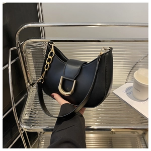 Close-up of black crescent shoulder bag with golden U-shaped buckle and side chain detail