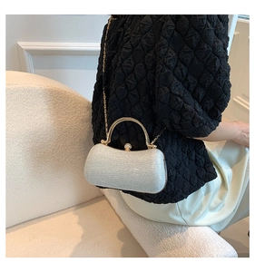 Silver glitter evening bag with gold handle and pearl clasp worn as a crossbody bag