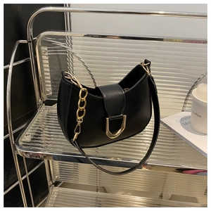 Detail of black half-moon hobo bag with golden horseshoe buckle and chain strap