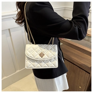 Detailed view of white quilted crossbody bag featuring a golden twist-lock and chain strap