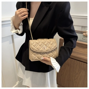 Detail of beige quilted chain bag featuring a gold geometric lock and elegant diamond pattern
