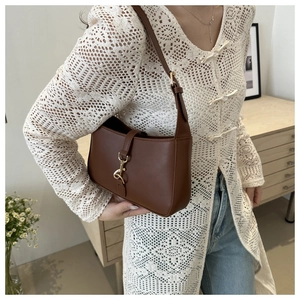 Detail of a brown matte leather shoulder bag with a bright gold hook buckle clasp