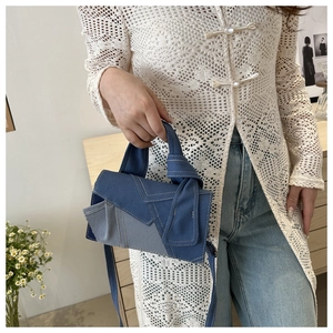 Detail of denim patchwork crossbody bag with contrast stitching and unique knot handle