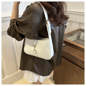 White shoulder bag with gold horsebit detail styled on a model in a leather jacket