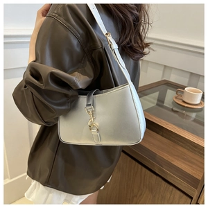 Detail of a metallic silver baguette bag with gold metal buckle shown on a model
