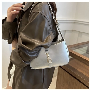 Detail shot of the silver metallic shoulder bag featuring a stylish golden metal clasp