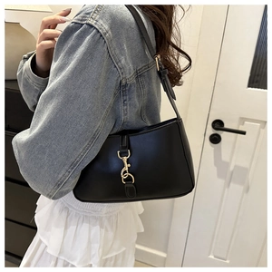 Detail of black leather hobo bag with gold lobster clasp worn with denim jacket