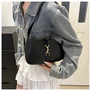 Detail shot of black leather underarm bag with iconic golden piston clasp and strap