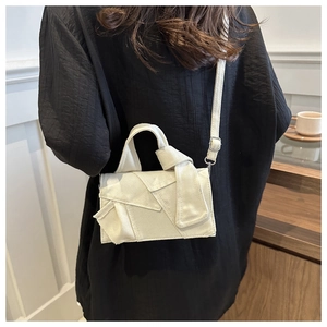 Detail shot of the cream canvas tote featuring geometric patchwork and decorative knot