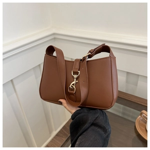Close-up of brown retro hobo bag with gold buckle and adjustable leather shoulder strap