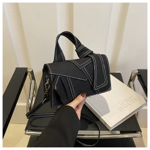 Detail of black denim patchwork small square bag with white contrast stitching