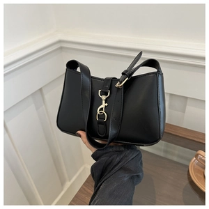 Detail of black leather hobo bag featuring iconic gold piston clasp and adjustable strap