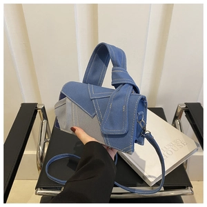 Detail of blue and grey patchwork handbag with yellow stitching and metal hardware