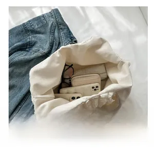 Internal view of cream pleated canvas tote bag showing storage for phone and wallet