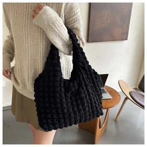 Detailed view of the 3D popcorn texture on a black minimalist shoulder tote bag