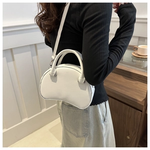 White shell crossbody bag with adjustable strap shown on model in modern room