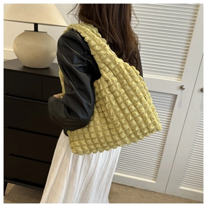 Model showing a vibrant yellow popcorn pleated fabric shoulder tote bag with soft texture