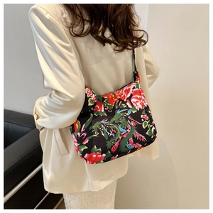 Close-up of a floral tote bag with dragon patterns worn on a beige blazer shoulder