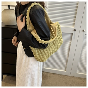 Detail of yellow cloud puff shoulder bag with ruffled strap on a model indoors