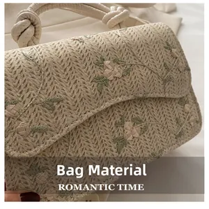 Detail of woven straw handbag featuring floral embroidery and knot handle