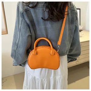 Vibrant orange crescent leather handbag shown in a lifestyle setting on a model back