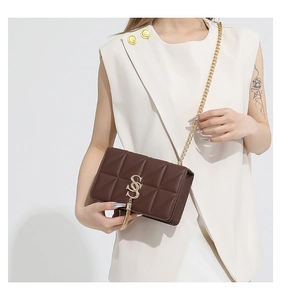 Detailed macro view of quilted dark brown leather bag with golden tassel and chain