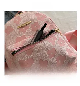 Detail of pink floral jacquard backpack showing front zip pocket with beauty product