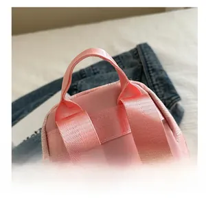 Detailed close-up of pink flower backpack top handle with woven straps and nylon texture