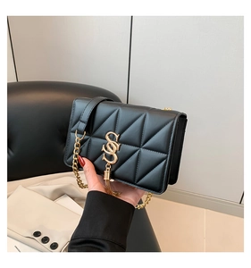 Detail of black quilted shoulder bag featuring gold S-logo, tassels, and chain strap