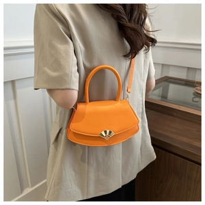 Détail du sac bandoulière orange avec fermoir doré en éventail et poignée ronde
