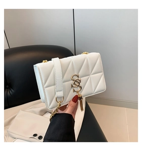 Close-up of white quilted shoulder bag featuring golden SS logo and fringe tassel detail