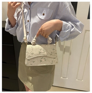 Detailed embroidery on cream woven crossbody bag with rustic knot handle