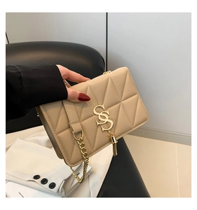 Detail of beige quilted shoulder bag featuring gold SS logo and tassel charm detail