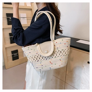 Detail of woven straw tote bag featuring pearl buckle and colorful dotted embroidery