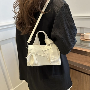 Minimalist cream canvas square handbag with twisted knot design shown on shoulder