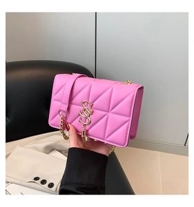 Detail of pink quilted shoulder bag with gold S-logo, tassel charm and chain strap