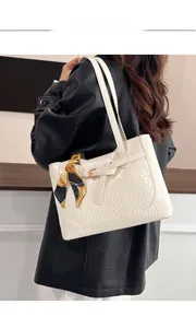 Detail of white faux leather bag with crocodile pattern and decorative silk scarf