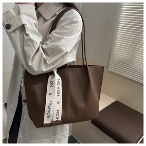 Detail of coffee brown tote bag with fashion ribbon strap worn by a model