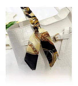 Detail of white crocodile texture tote bag with elegant printed scarf on handle