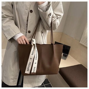 Dettaglio borsa tote marrone con elegante nastro bianco decorativo sul manico